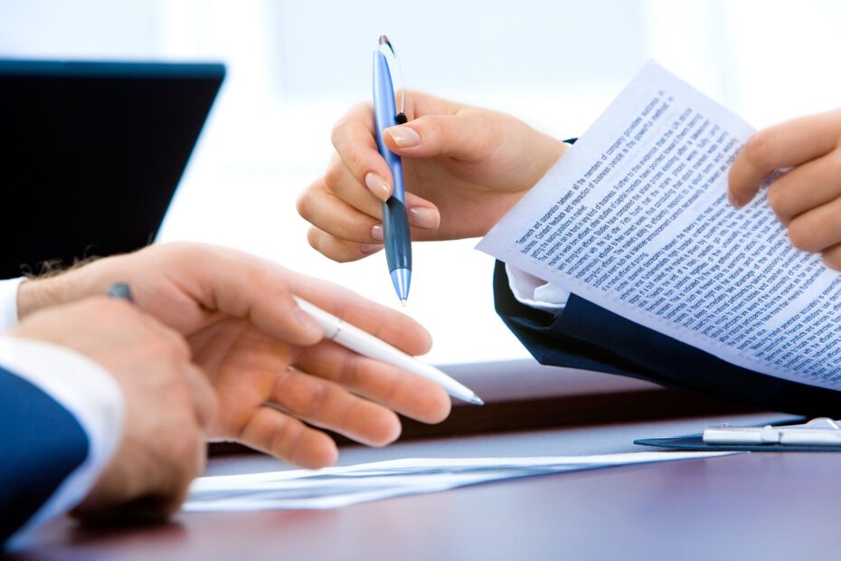 pen and paper in persons hand in meeting.